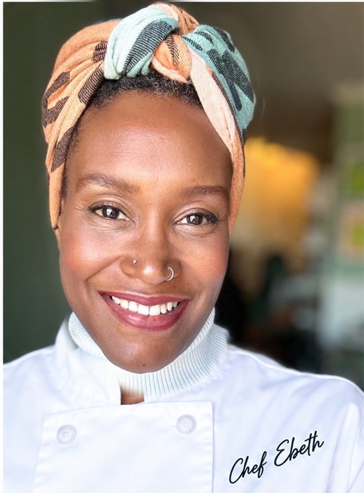 Ebeth smiling in chef attire in a warm modern kitchen