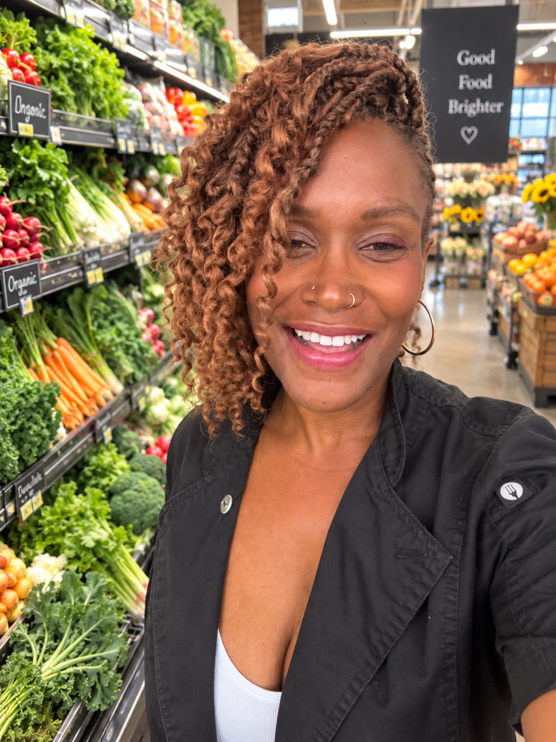 Ebeth smiling in a colorful grocery store produce aisle